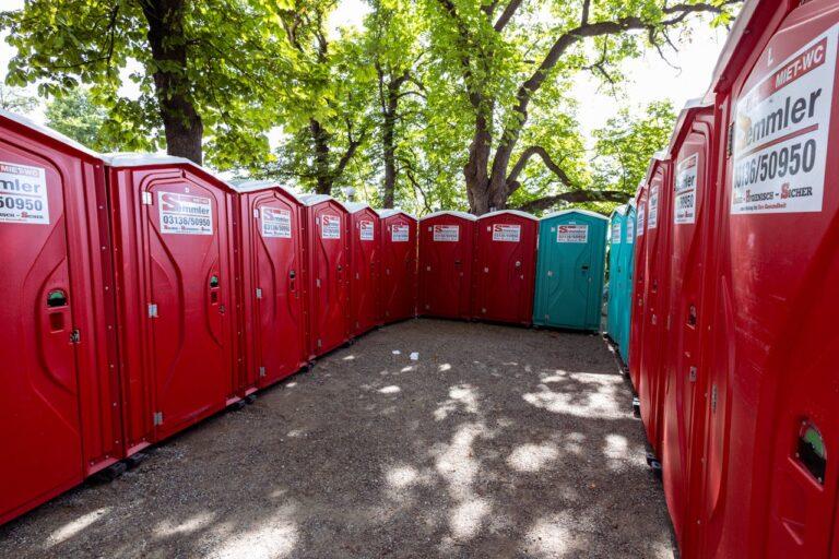 A group of red and teal portable toilets